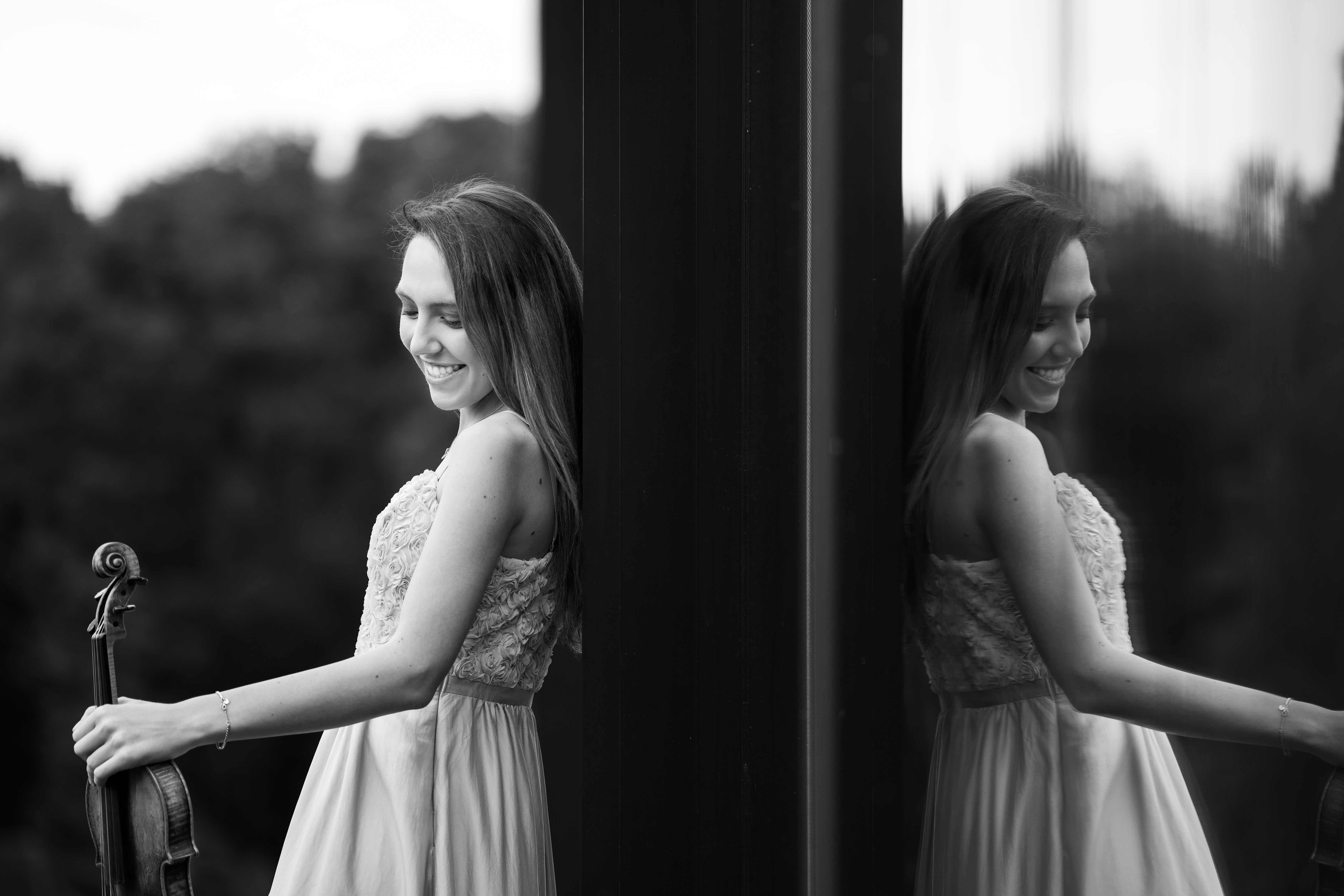 Alexandra Cooreman leaning against a window holding her violin.